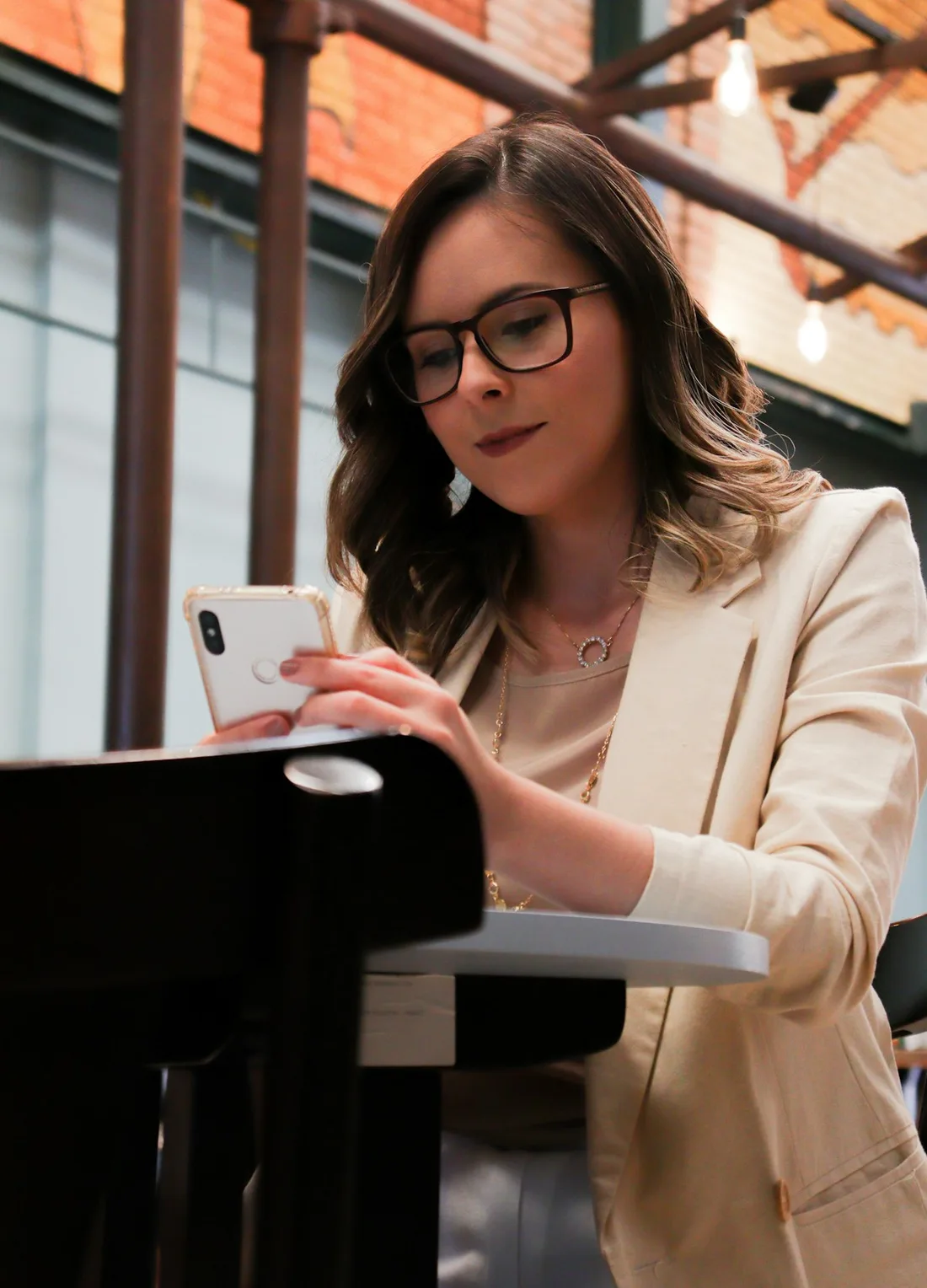 Mulher de blazer atendendo pelo celular ao lado do laptop