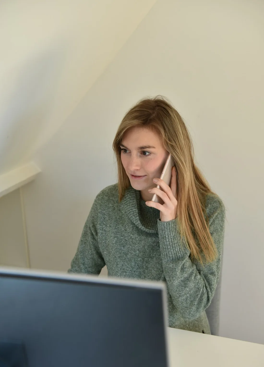 Mulher ao telefone diante do computador no fim do dia